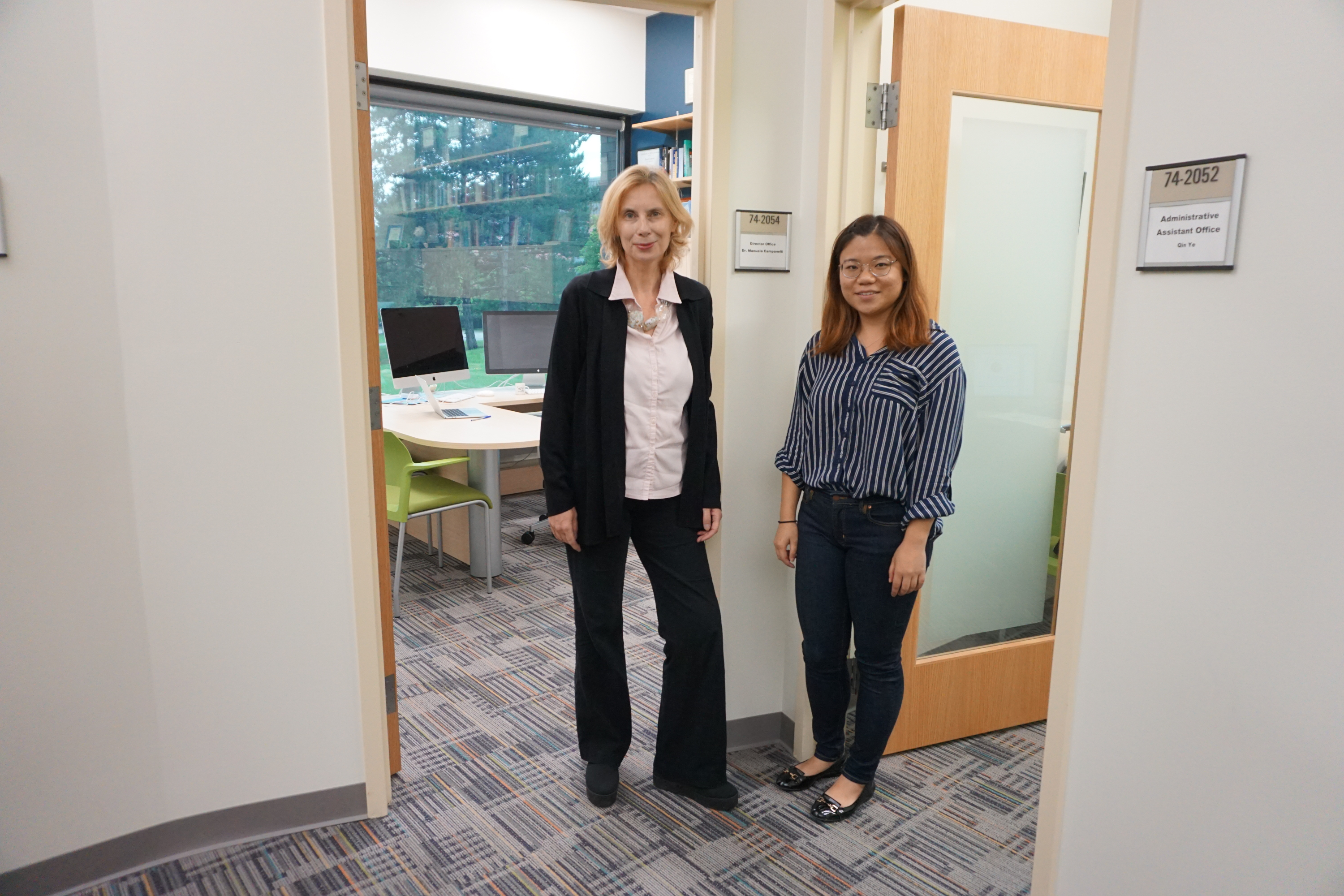 CCRG Director Manuela Campanelli (left) and Financial & Admin Assistant Qin Ye (right) standing outside their offices.